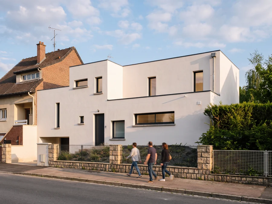 Façade blanche de la maison rue Dhavernas à Amiens, avec volumes en retrait et fenêtres verticales et horizontales.