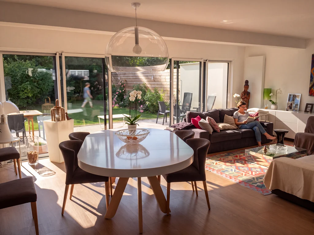 Salon et salle à manger réunis dans une pièce lumineuse, ouverte par une large baie vitrée sur la terrasse et le jardin.