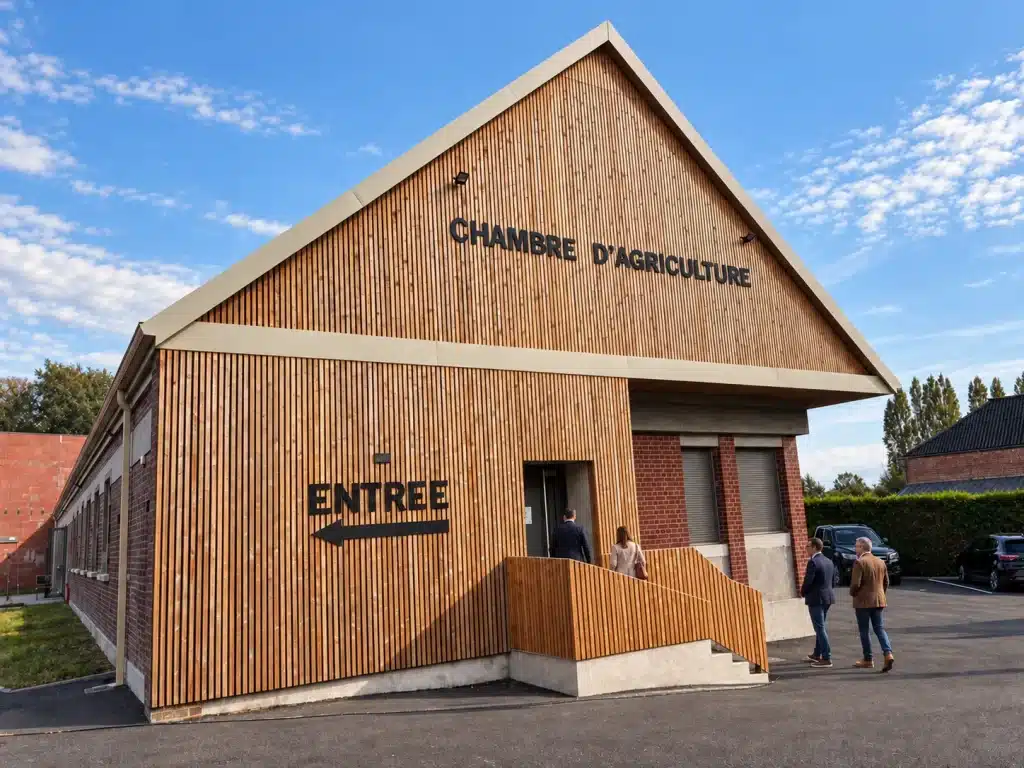 Entrée de la Chambre d'Agriculture de l'Oise après travaux : pignon en bardage bois vertical, rampe d'accès et enseigne, architecture de réhabilitation à Grandvilliers