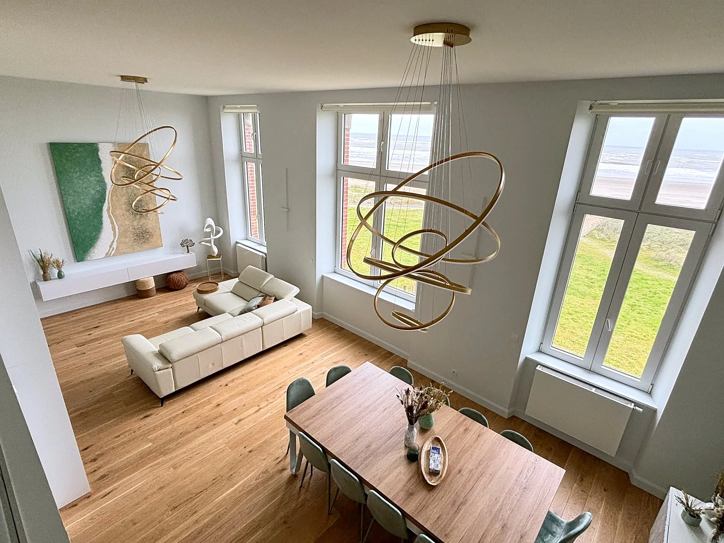 Séjour en double hauteur d'un appartement de la Tour A d'Altéia à Berck-sur-Mer, vu depuis la mezzanine, fenêtres sur la dune et la mer